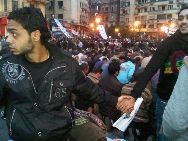 Slavná momentka z Egypta roku 2011 -- koptští křesťané chrání modlící se muslimské spoludemonstranty před policií. Foto Nevine Zakiová